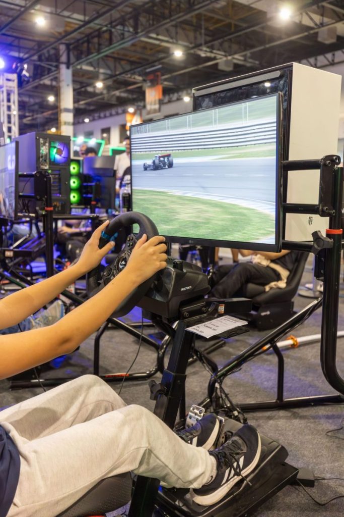 A person confidently navigates a virtual race simulator at an indoor gaming event.